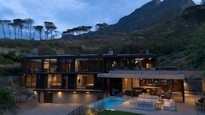 A modern two-story house with large glass windows, a pool, and a mountainous backdrop. - Tarentaal Kloof Villa in Higgovale (Cape Town)