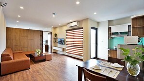 Un salon moderne avec un canapé, une table basse et un coin repas avec une table dressée pour quatre personnes.