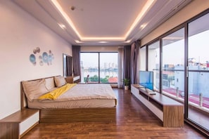 A modern bedroom with a large bed, a TV, and a view of a cityscape through large windows. - Luxe Paradise Residence Nhat Chieu (Hanoi)