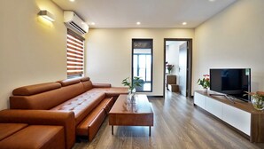 Un salon moderne avec un canapé en cuir marron, une table basse en bois et un téléviseur à écran plat posé sur un meuble en bois.