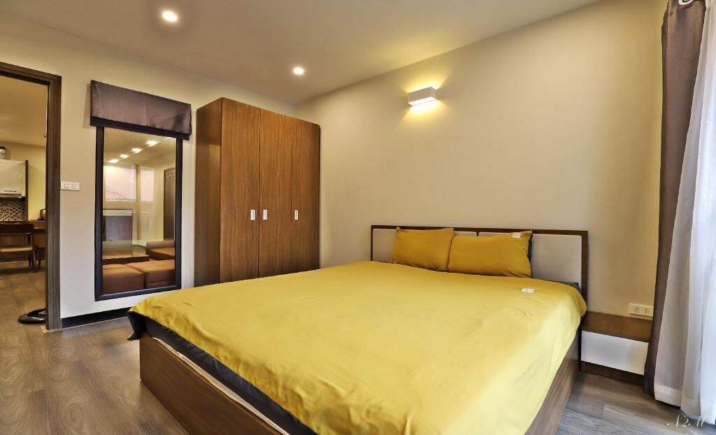 A bedroom with a large bed, wooden wardrobe, and a mirror.