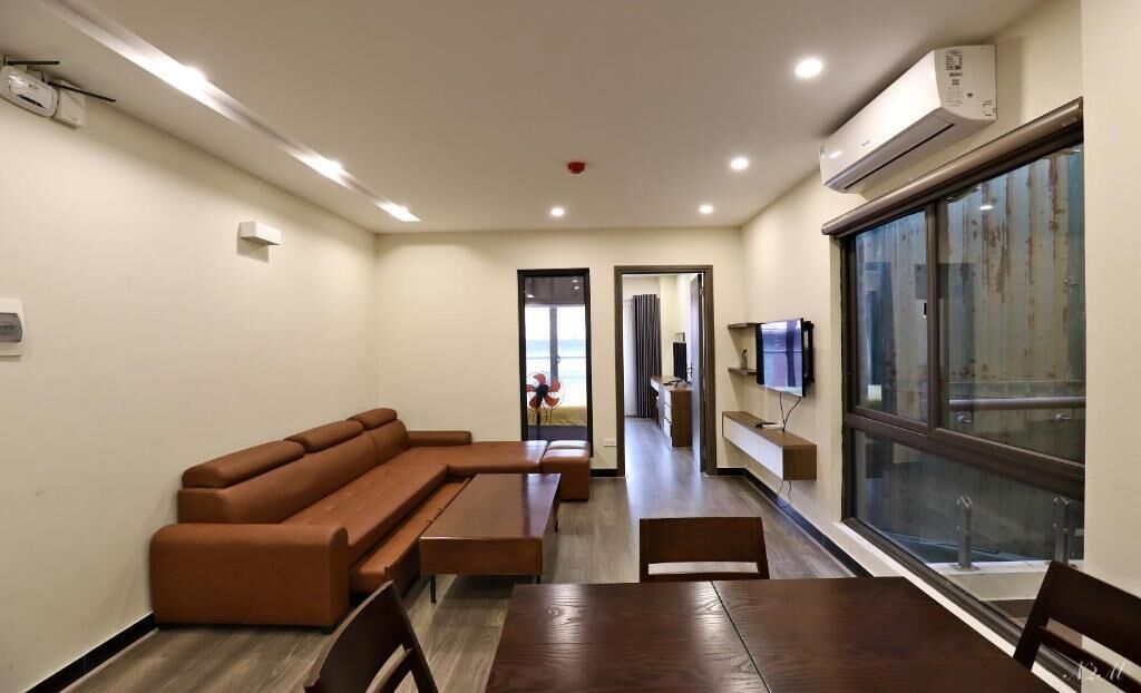 Una sala de estar moderna con un sofá, una mesa de comedor y un televisor montado en la pared.