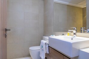 A modern bathroom with a white sink, a mirror, and a toilet.