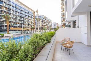 A modern residential building with a pool, outdoor seating, and lush greenery.