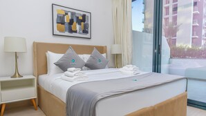 A hotel room with a bed, two bedside tables, a lamp, a painting, and a view of a building.