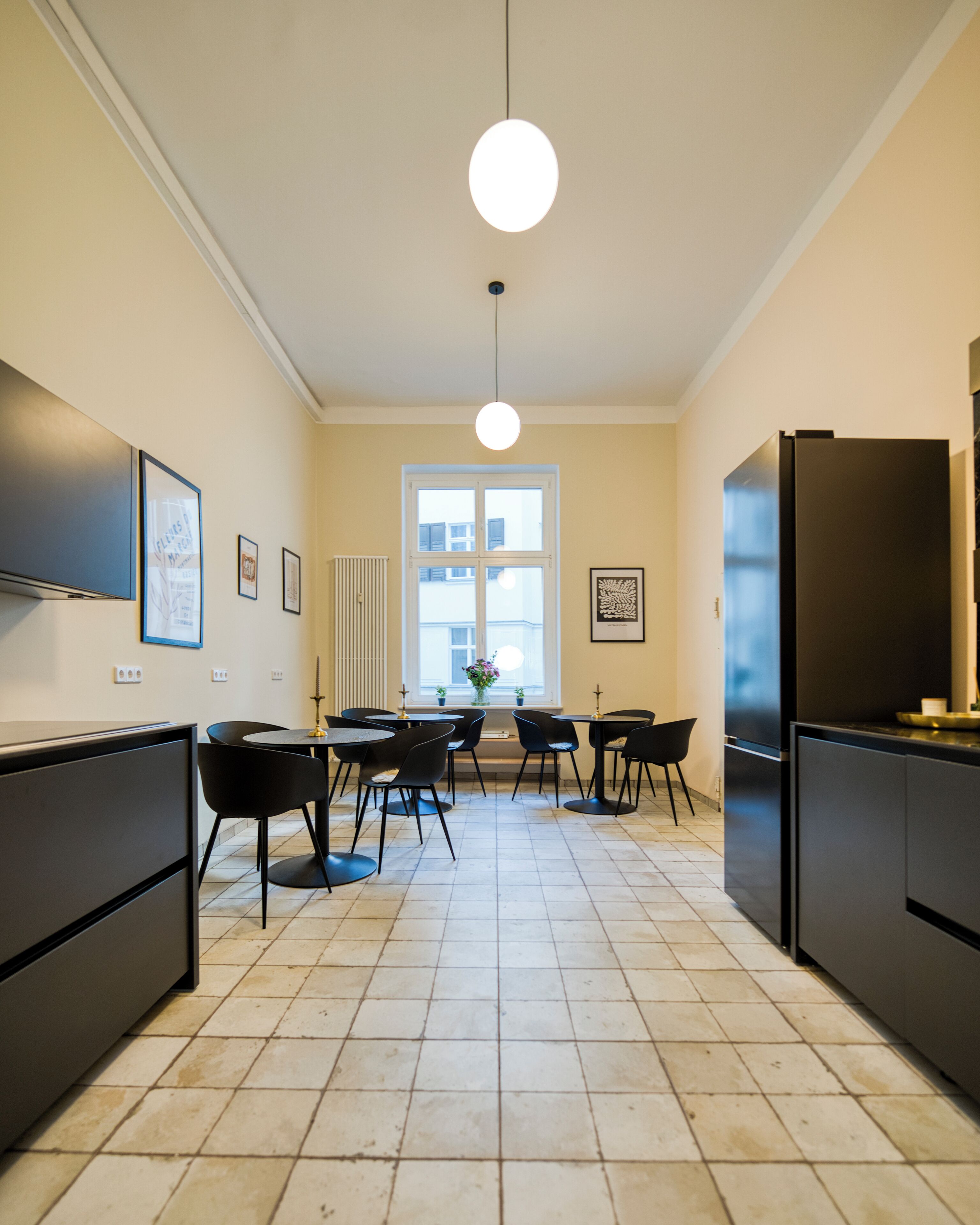 Una cocina moderna con una isla central, electrodomésticos negros y suelo de baldosas.