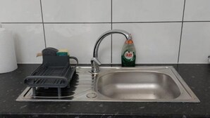 Cuina amb un vàter d'acer inoxidable, un escorredor i una ampolla de detergent Fairy.