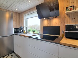 A modern kitchen with a built-in oven, a coffee maker, and a window with a view of greenery.