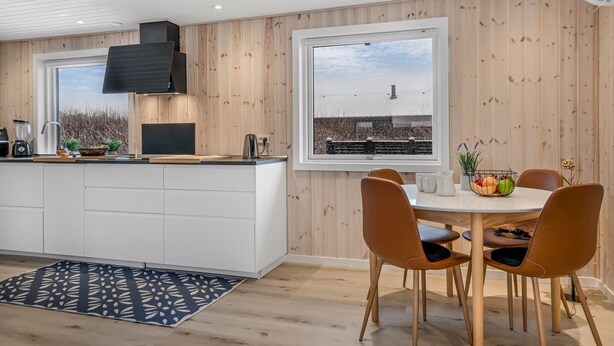 Eine moderne Küche mit einer zentralen Kochinsel, Holzwänden und einem großen Fenster mit Blick auf eine Stadtlandschaft.