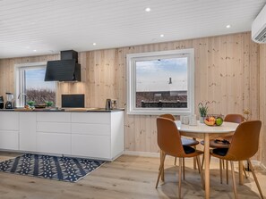 A modern kitchen with a central island, wooden walls, and a large window overlooking a cityscape. - "Annukka" - 500m from the sea by Interhome (Løkken)