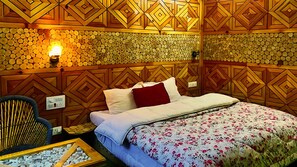 A room with a bed, a chair, and a wall covered with logs. - Undiscovered Mountains Hotel (Banjar)