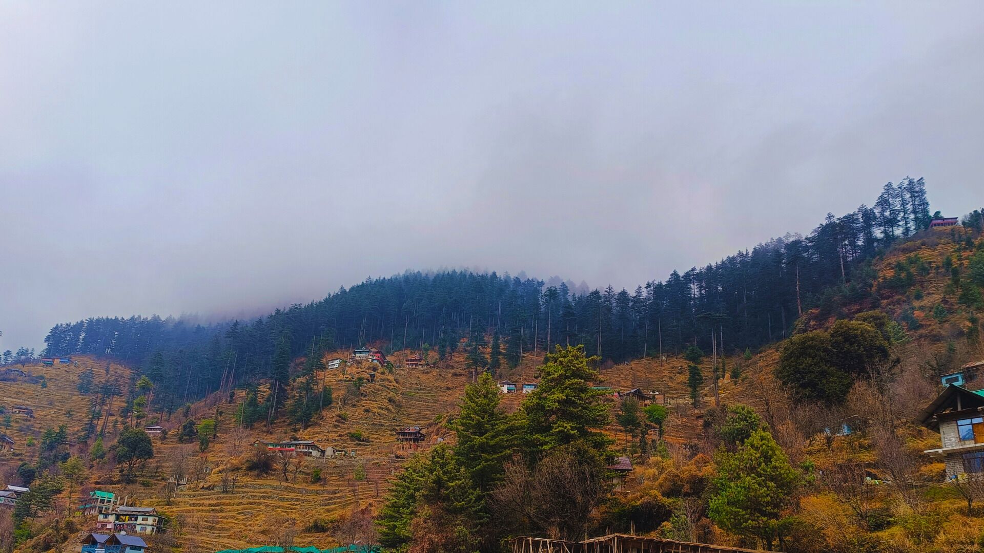 A mountainous landscape with terraced fields and scattered houses.