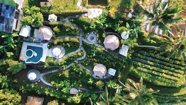 Ovenfra ses et resort med flere swimmingpools, skyggefulde områder og frodig vegetation.