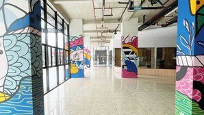 A modern corridor with colorful murals on the walls, a polished marble floor, and a clear exit sign. - Apartement Urbano by NamRoom (Bekasi)
