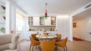 A modern kitchen with white cabinets, a dining table with chairs, and a hanging light fixture.