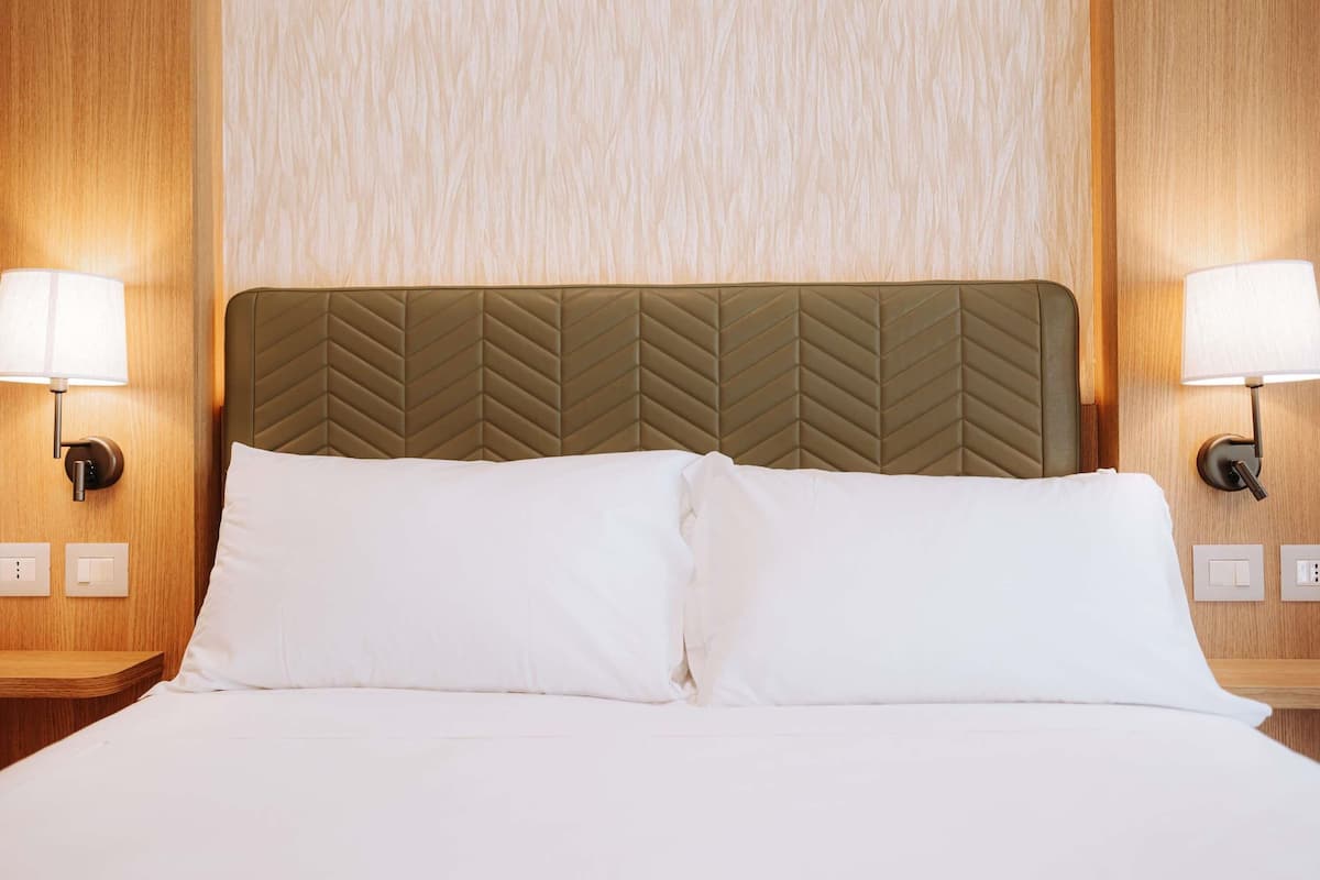 Ein Hotelzimmer mit einem Bett, zwei Nachttischlampen und einer Holzwand.