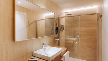 A modern bathroom with a large mirror, a sink, and a glass-enclosed shower.