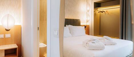 Hotelkamer met een bed, nachtkastje, wandlamp, spiegel en douche.