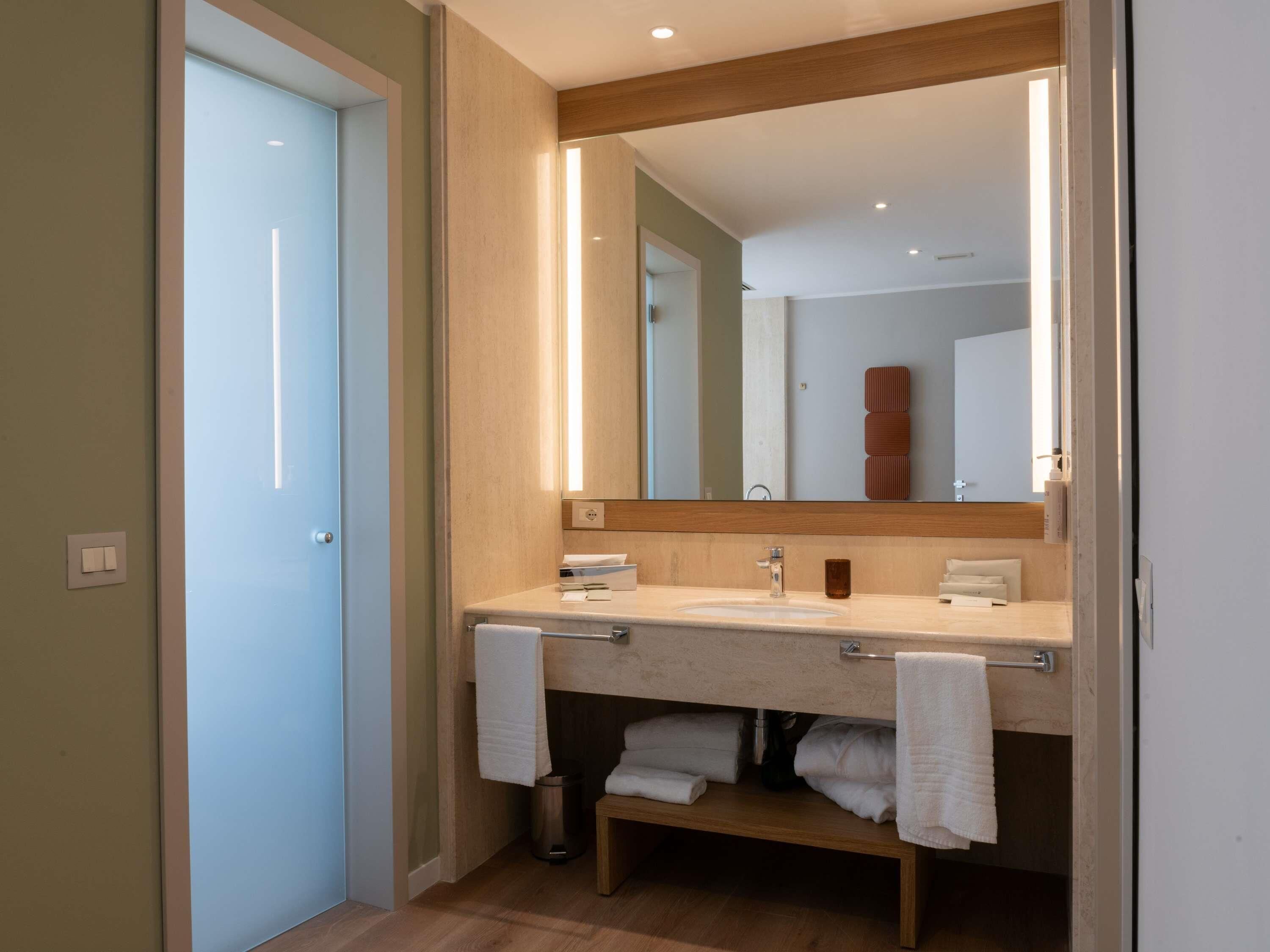 Uma casa de banho moderna com um espelho grande, duas lavatórios e um porta-toalhas.