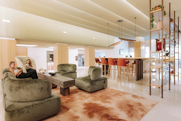 A spacious living area with a large sofa, a coffee table, and a cowhide rug. There are multiple chairs and a dining table in the background. - Mövenpick Hotel Bari (Bari)