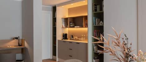 Un intérieur moderne avec une table à manger en bois, une chaise, une bibliothèque et un vase contenant des plantes séchées.