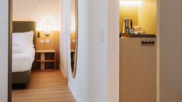 A hotel room with a bed, bedside table, and a small seating area. There is a kitchenette with a coffee maker and a microwave.