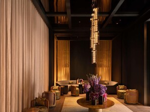 A modern interior with a central seating area, a round table with floral centerpieces, and a unique chandelier. - Raffles Sentosa Singapore (Singapore)