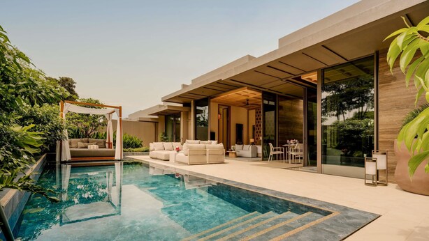 Un'area piscina moderna all'aperto, con una piscina cristallina, una zona salotto coperta e una vegetazione rigogliosa.
