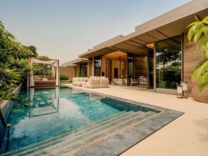 A modern outdoor pool area with a clear pool, a covered seating area, and lush greenery. - Raffles Sentosa Singapore (Singapore)