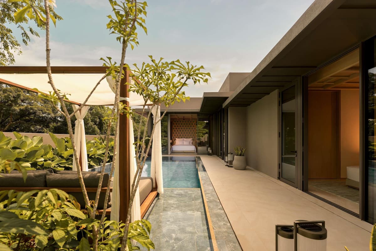 A modern outdoor pool area with a clear view of the pool, a seating area, and a pathway leading to a building entrance.