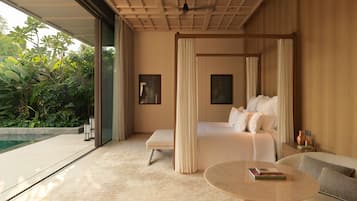 Un dormitorio con una cama grande, una zona de estar con una mesa y vistas a zonas verdes.