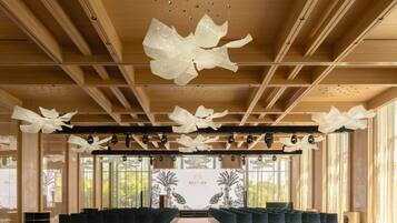 A spacious hall with rows of chairs, a large decorative ceiling feature, and a backdrop with a peacock illustration.