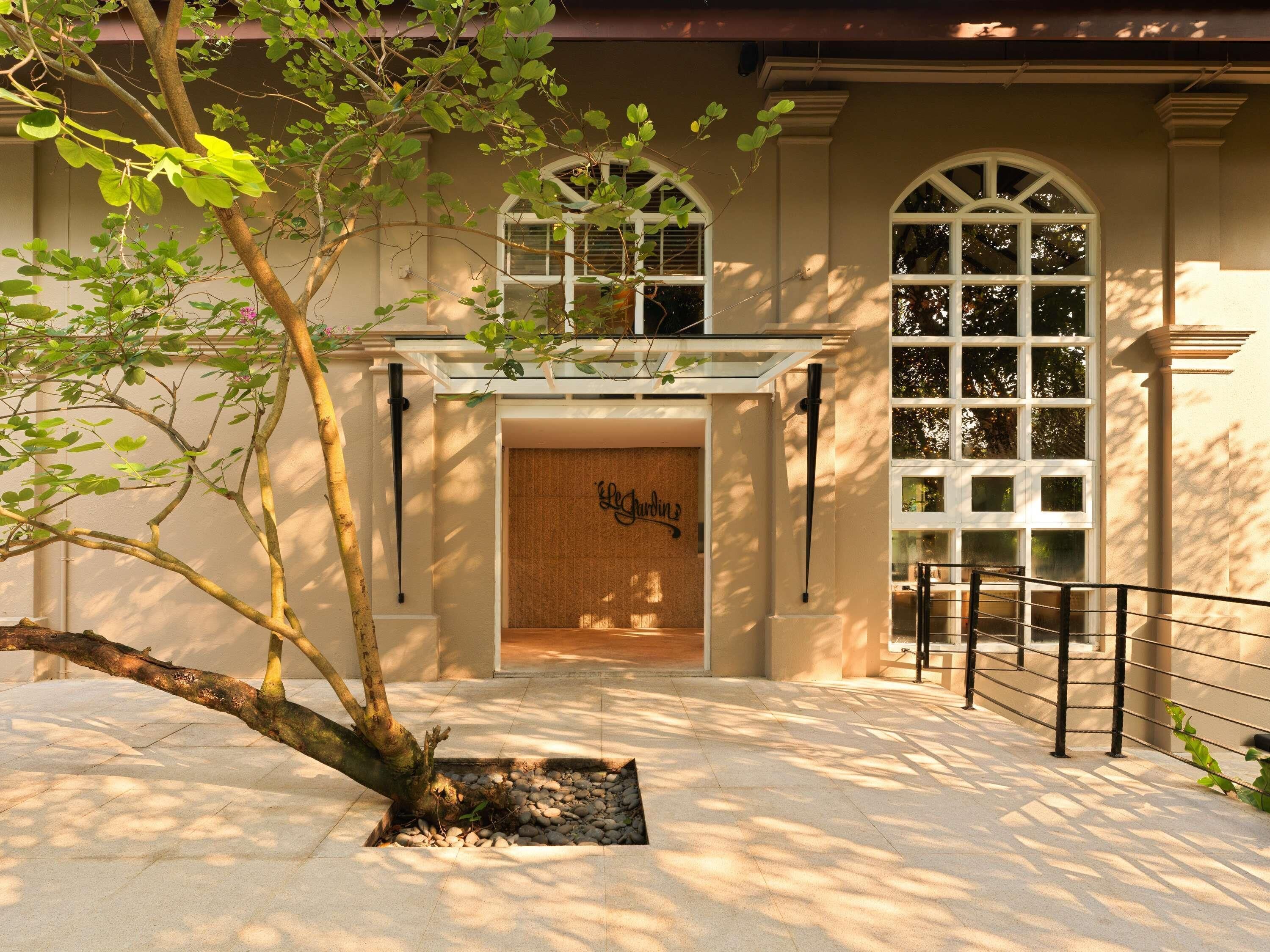 A building entrance with a tree, a sign, and a staircase.