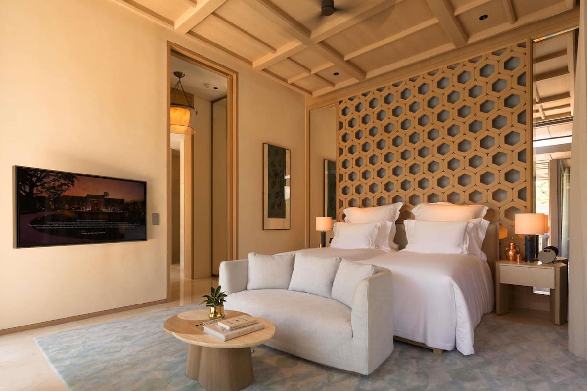 A bedroom with a bed, a sofa, a coffee table, and a wall-mounted artwork.