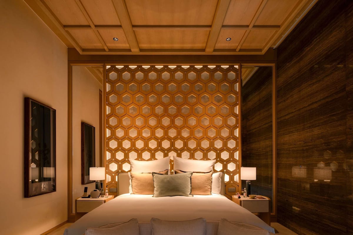 A modern hotel room with a large bed, two bedside tables, and a decorative wall panel.