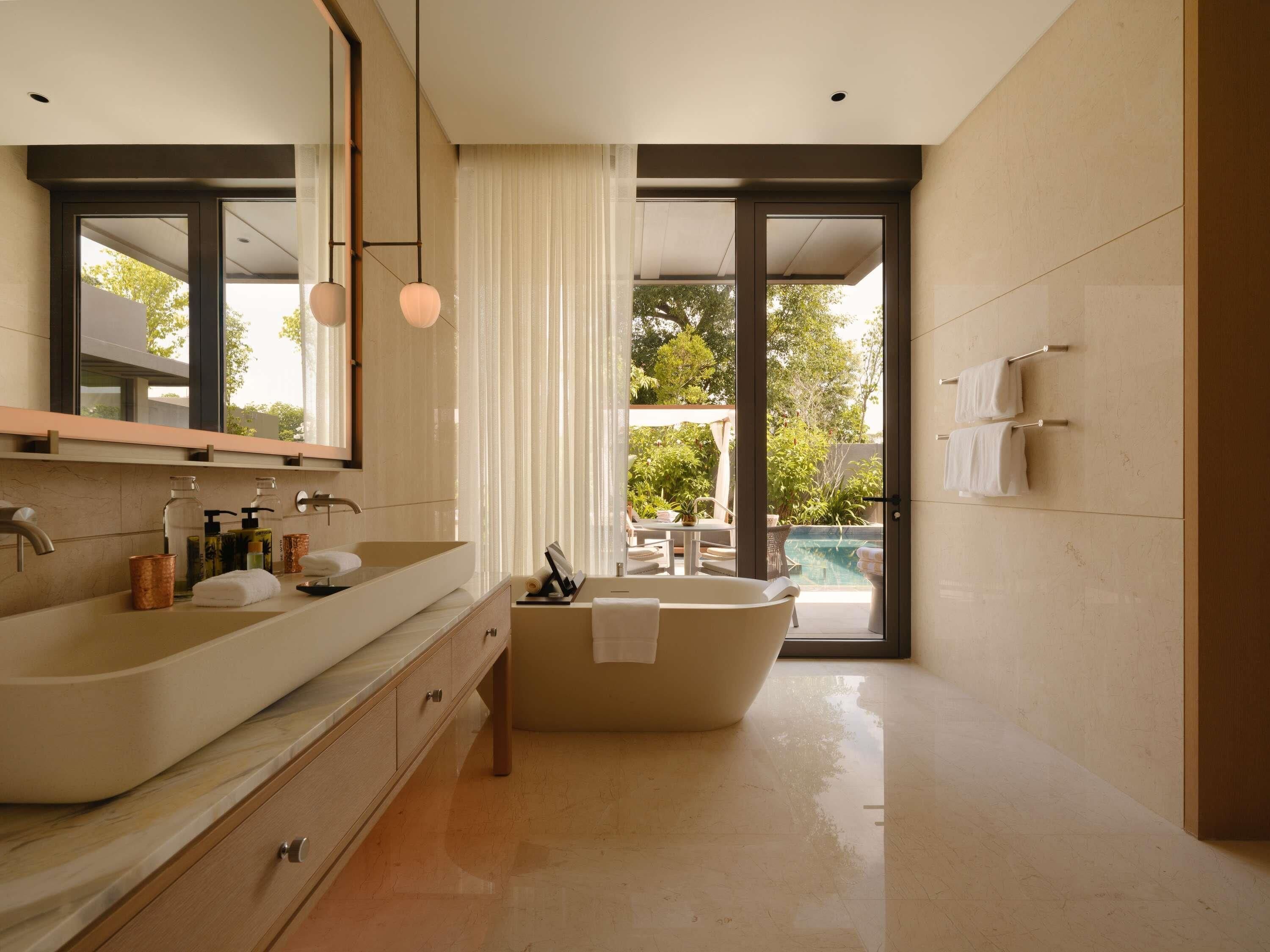 Une salle de bain moderne avec une grande baignoire, un meuble-lavabo à deux vasques et un grand miroir.