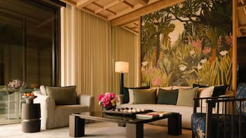 A modern living room with a glass coffee table, two sofas, and a large floral mural on the wall.