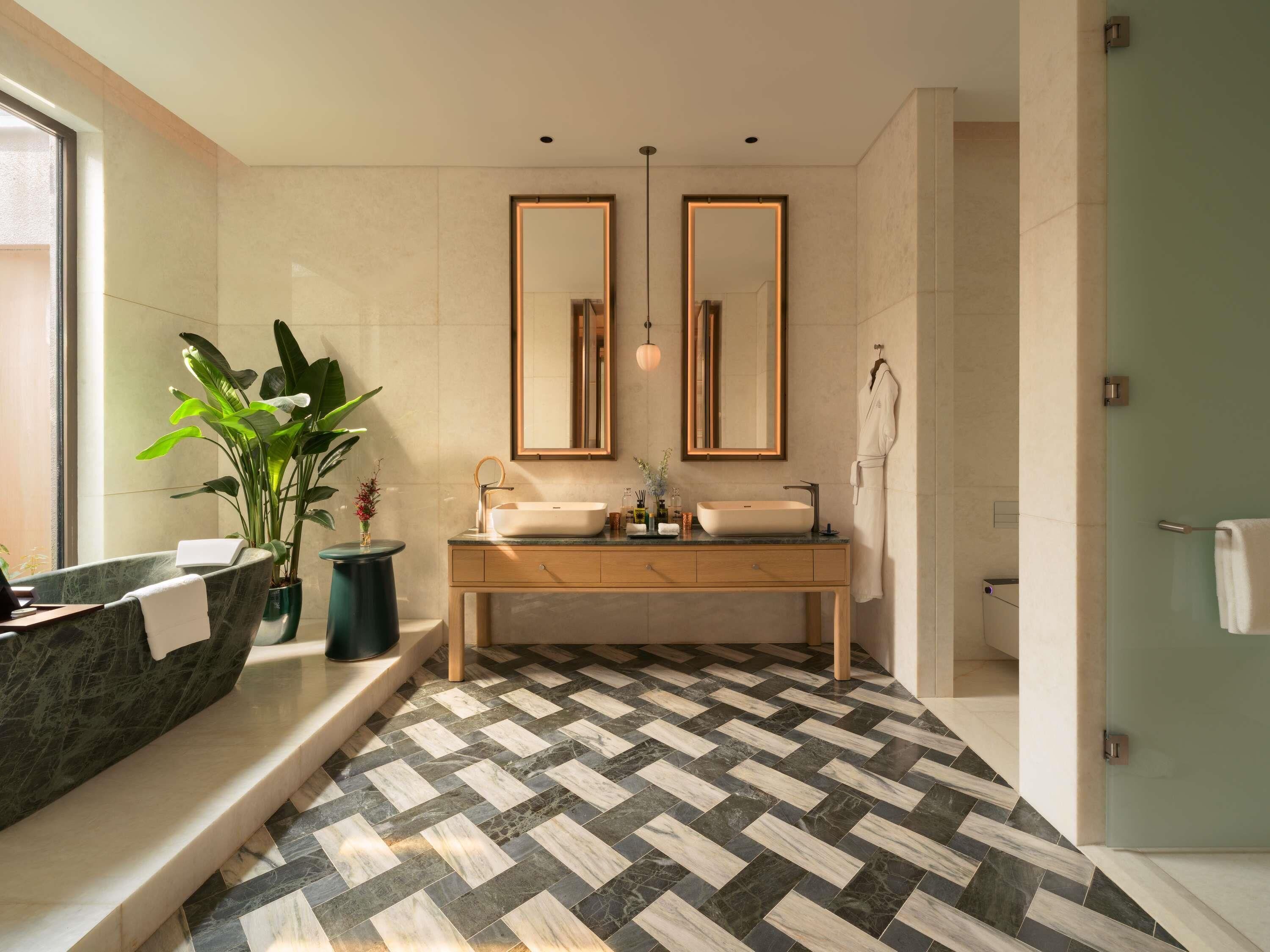 A modern bathroom with a herringbone floor pattern, a double vanity with a vessel sink, and a large mirror above the vanity.