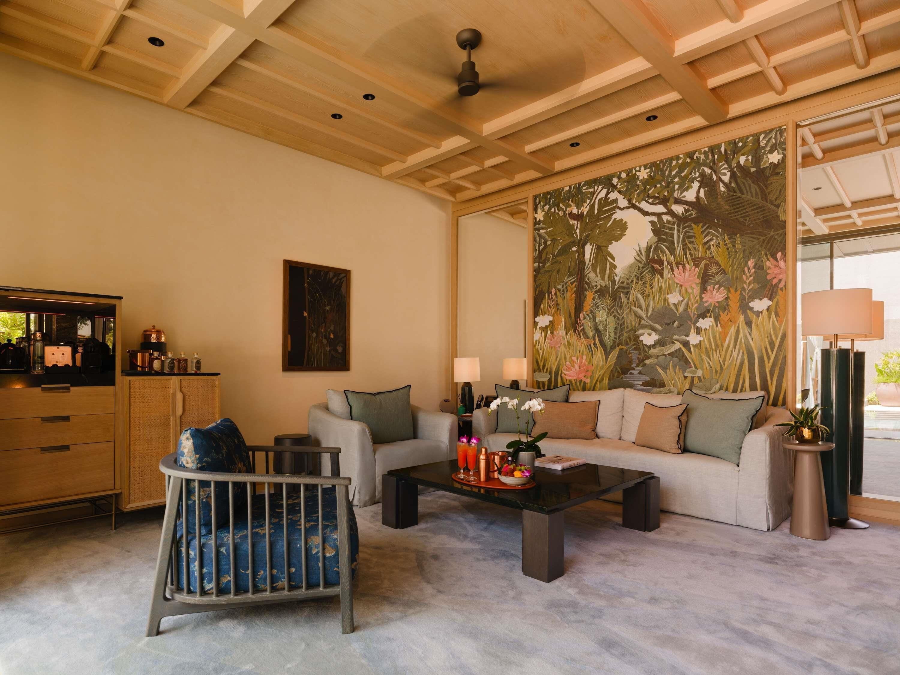 Un salon avec un canapé, une table basse et un berceau. Il y a un tableau au mur et une grande fenêtre.