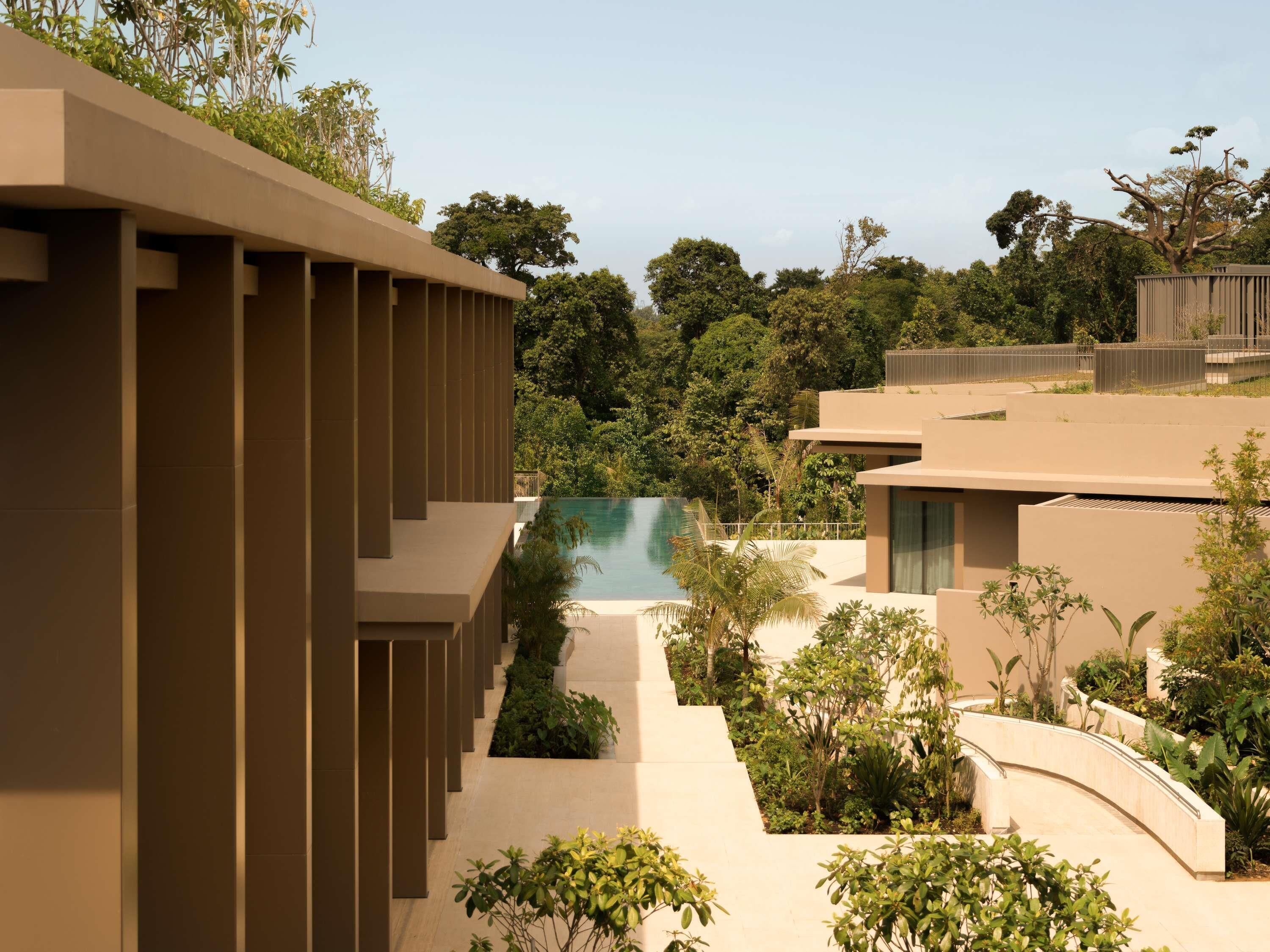 Een modern resort met een zwembad, weelderige begroeiing en een helder uitzicht op het omliggende bos.