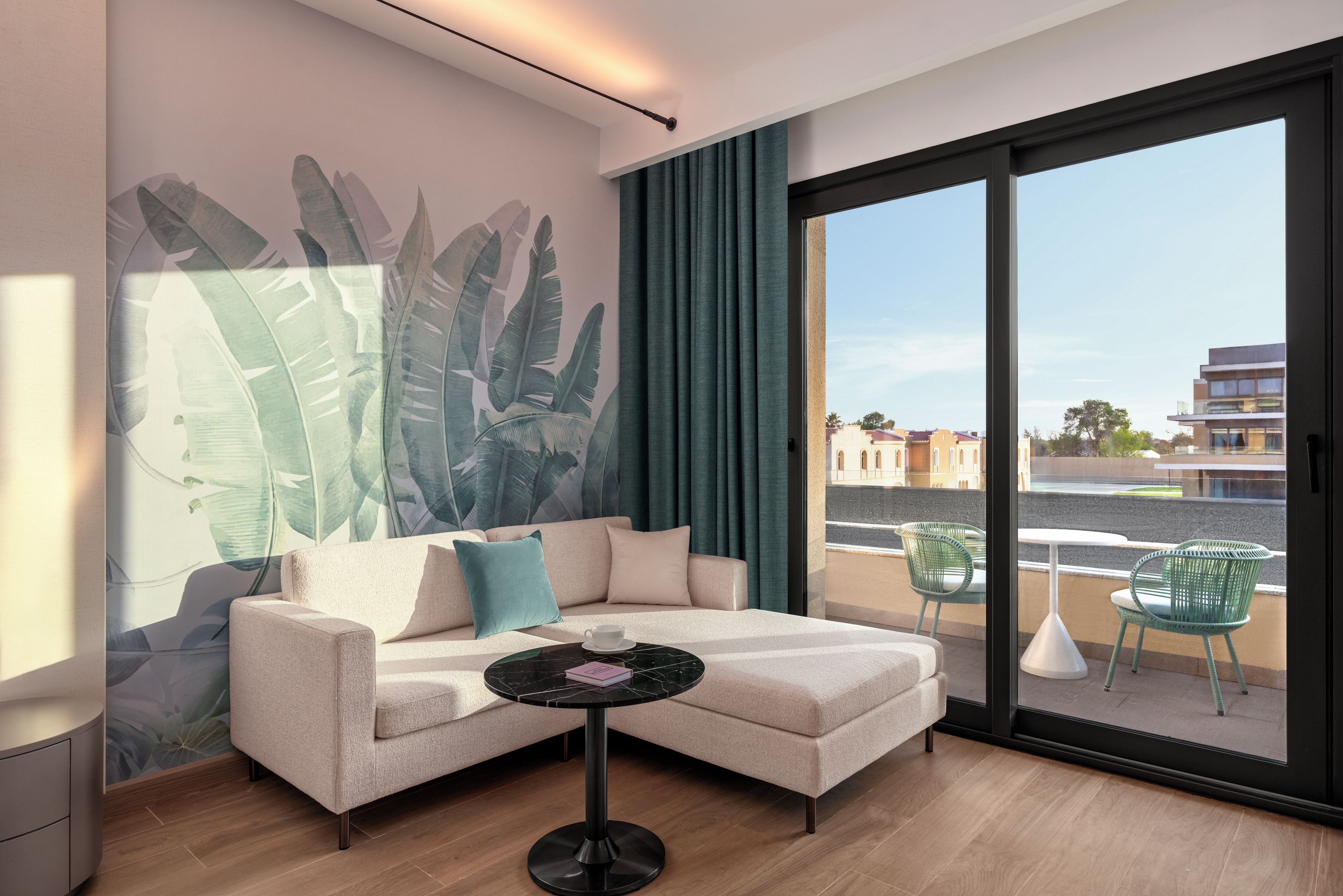 Una sala de estar moderna con un sofá, una mesa de centro y un amplio ventanal con vistas a edificios y una calle.