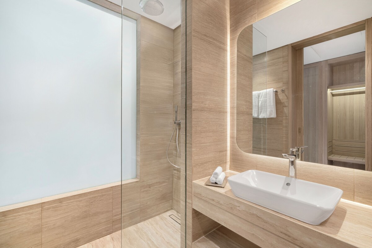 A modern bathroom with a glass shower enclosure, a white sink, and a large mirror.