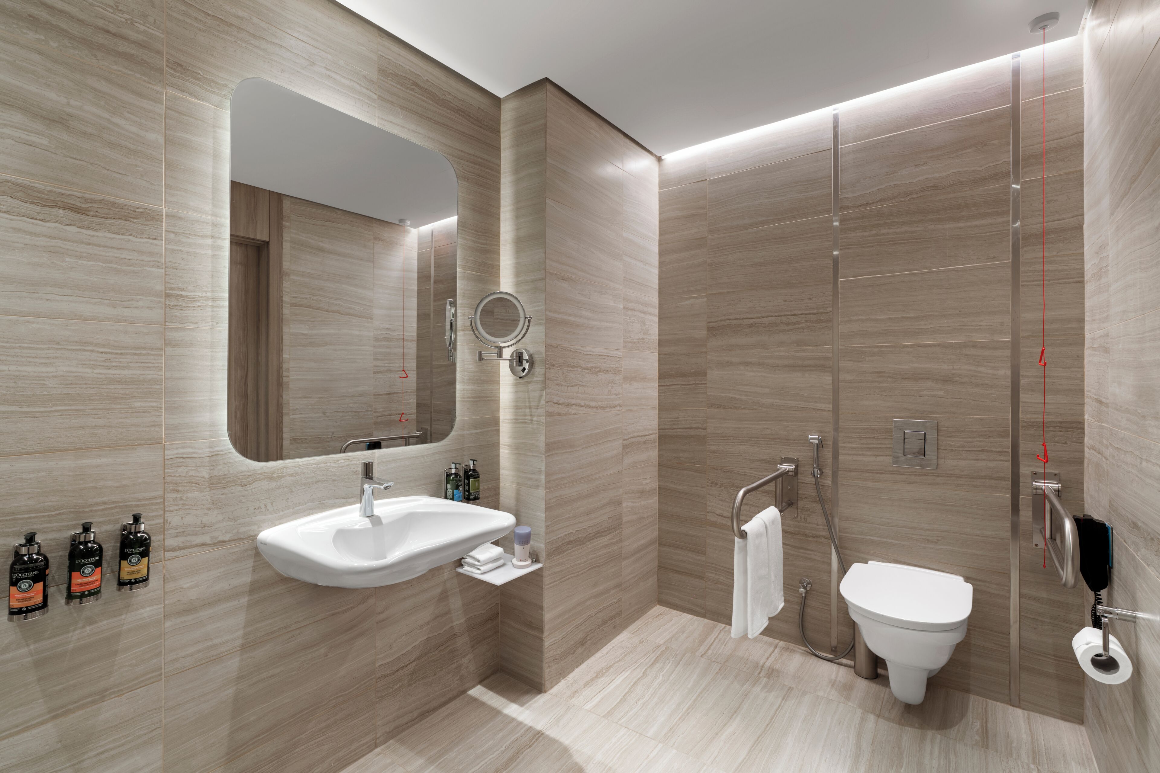 A modern bathroom with a large mirror, a sink, a toilet, and a shower.