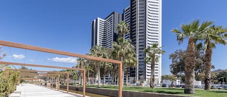 A modern urban park with a pavilion, palm trees, and a river.