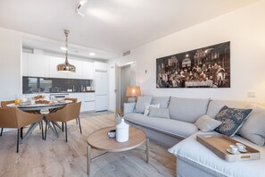 Una sala moderna con un sofá, una mesa de comedor con sillas, una mesa de centro y un cuadro en la pared.