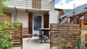 Une clôture en bois, un banc et une table dans une cour intérieure avec une porte et des fenêtres.