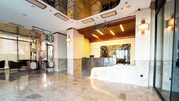 Una hall moderna con reception, area salotto e pavimento in marmo.