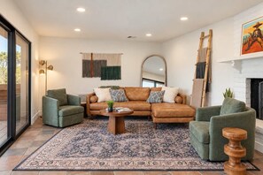The living room has a leather sectional, two green swivel chairs, and a fireplace. Gather everyone here to talk about the day's adventures. - Uptown Red Rock Retreat | Hot Tub & Patio Views (Sedona)