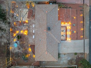 Vue aérienne d’un bâtiment doté d’un toit recouvert de tuiles, d’un espace extérieur aménagé pour s’asseoir et d’un éclairage décoratif.