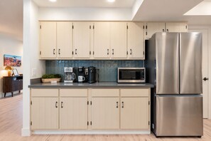 A modern kitchen with light-colored cabinets, stainless steel appliances, and a flat-screen TV. - Uptown Red Rock Retreat | Hot Tub & Patio Views (Sedona)